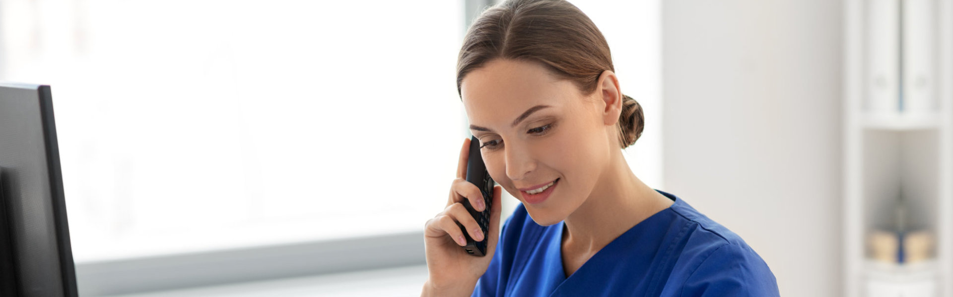 happy smiling female nurse with computer and clipboard calling on phone at hospital